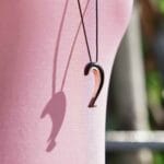 A woman wearing a pink top displays a distinctive black and rose plated 2022 necklace, perfect for elevating holiday fashion in 2022.